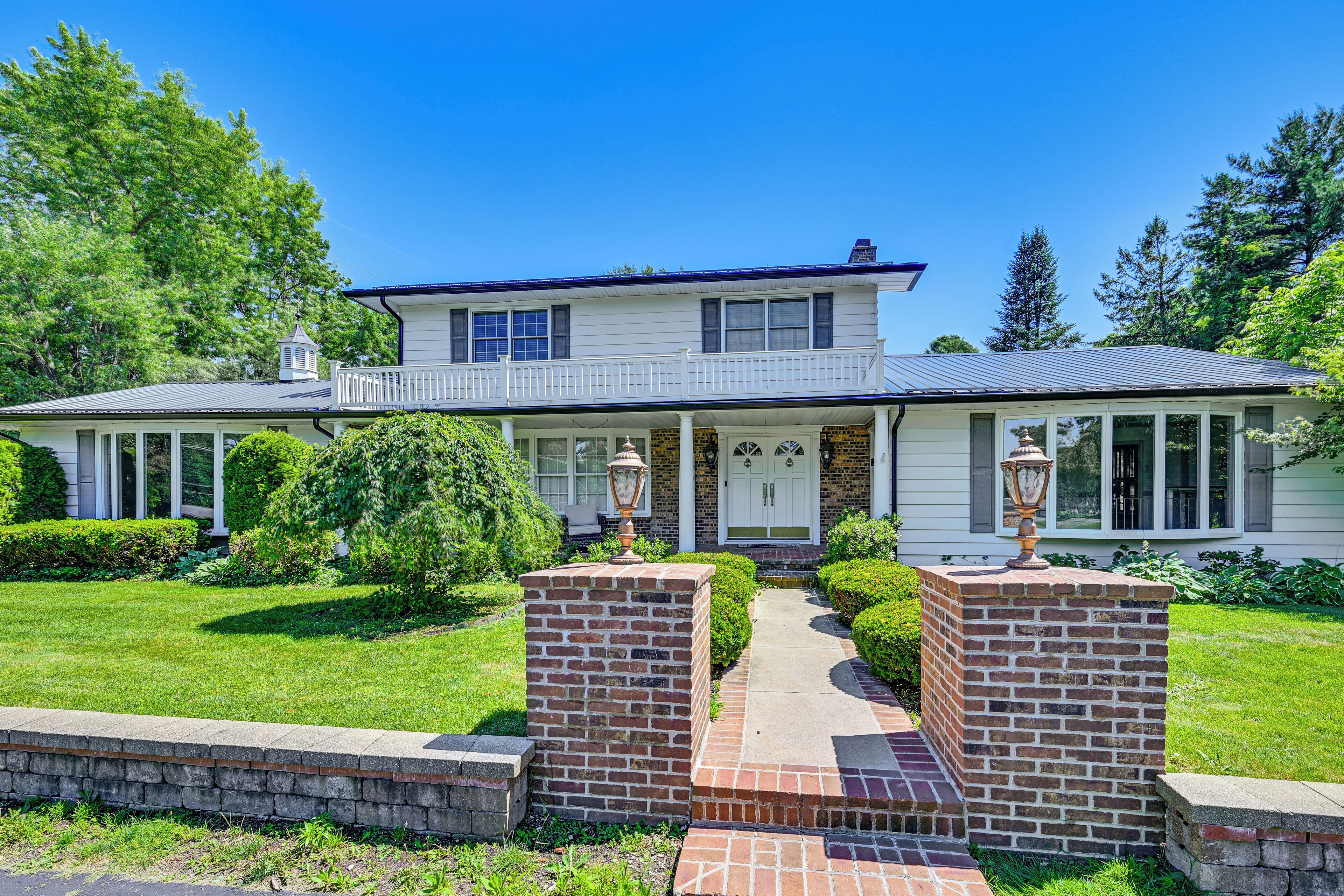 A two-story house with a front porch, a brick entrance, and a well-maintained lawn.