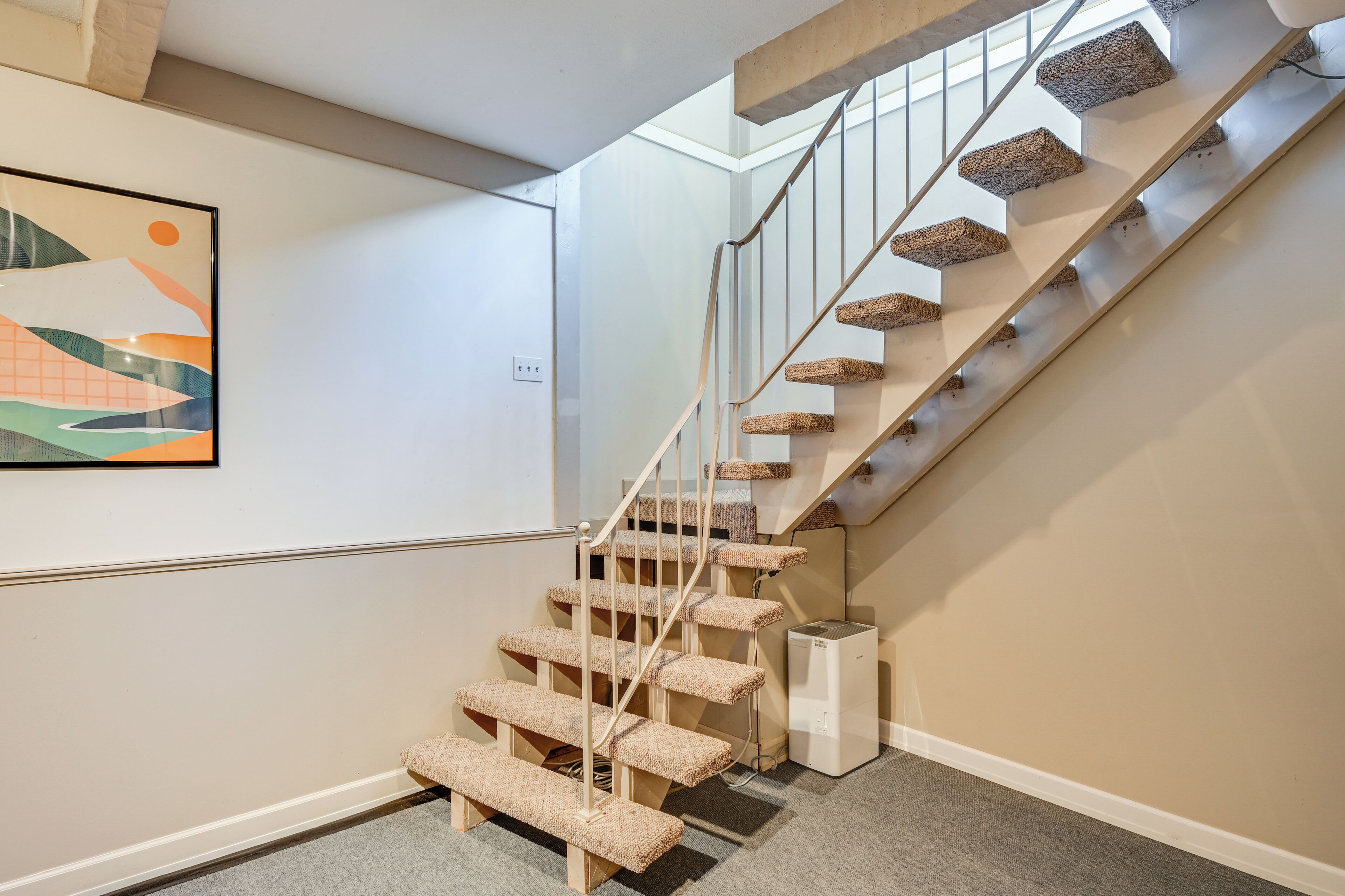 A staircase with wooden steps and a metal railing, leading to a landing with a small white object on the floor.