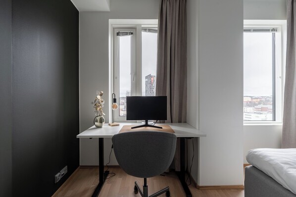 A modern bedroom with a desk, a chair, a bed, and a window with curtains. - 12th Floor Sauna Retreat with Views (Tampere)