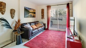 A living room with a red carpet, a leather sofa, a coffee table, and a TV stand. - Beautiful apartment, 10 minutes walk from the beach (Urbanización Estrella de la Bahía)