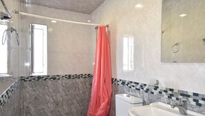 Ein Badezimmer mit Dusche, Toilette, Waschbecken und einem großen Spiegel.