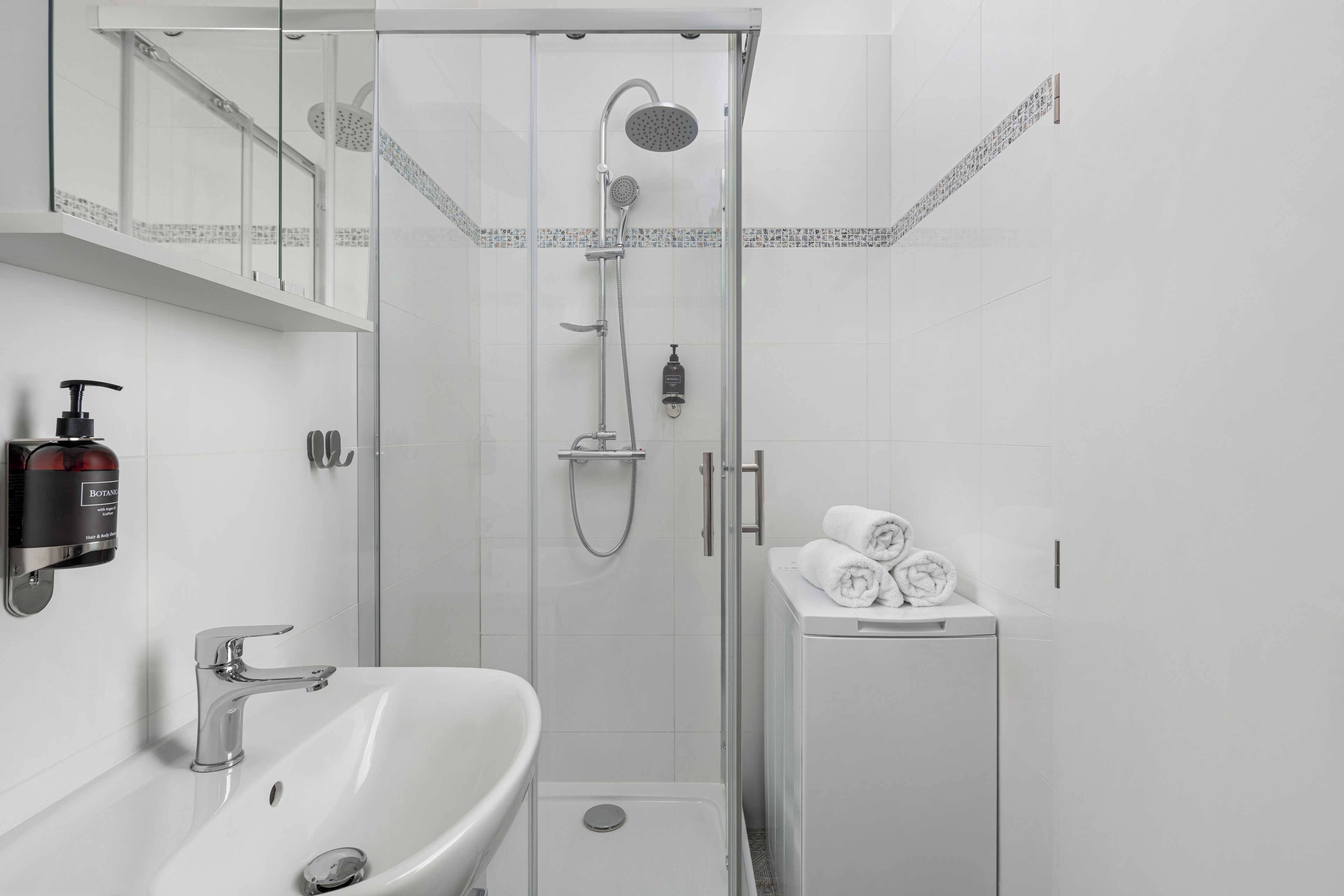 A modern bathroom with a glass-enclosed shower, a white sink, and a towel rack.
