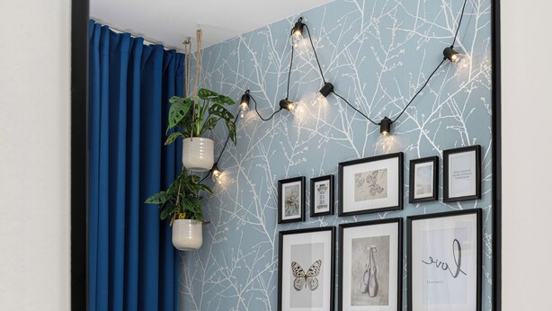 A bedroom with a bed, blue curtains, a wall-mounted plant, and framed artwork. - Enjoy Downtown Boutique Apartments #12 by Goodnite cz (Brno)