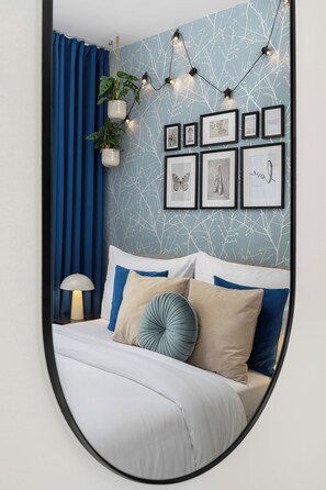 A bedroom with a bed, blue curtains, a wall-mounted plant, and framed artwork. - Enjoy Downtown Boutique Apartments #12 by Goodnite cz (Brno)