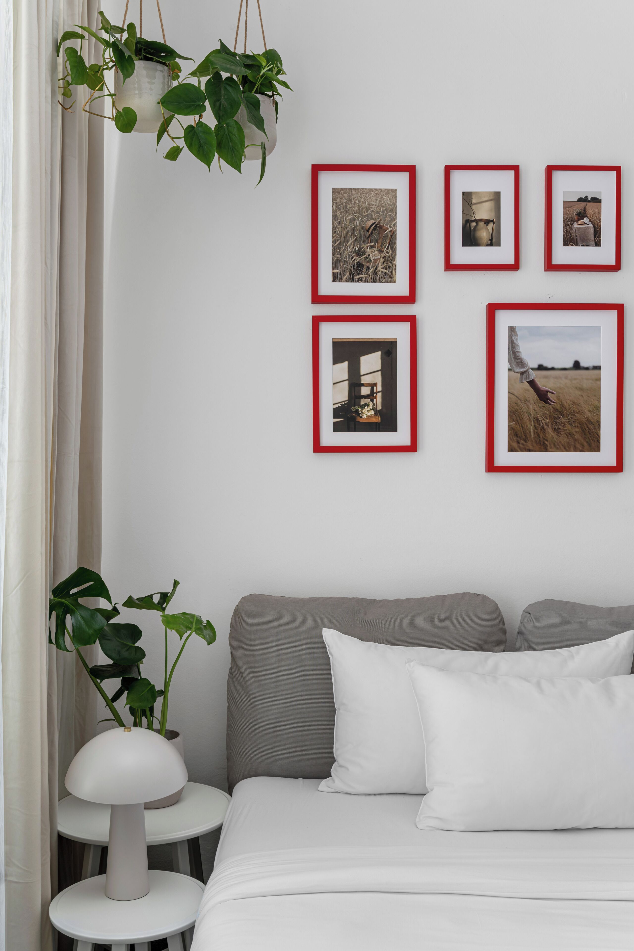 A bedroom with a bed, pillows, a bedside table with a lamp, and a wall with framed pictures.