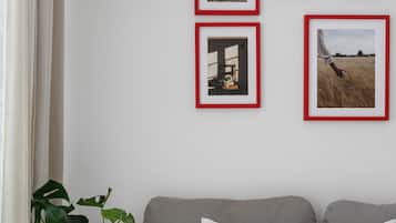 A bedroom with a bed, pillows, a bedside table with a lamp, and a wall with framed pictures.