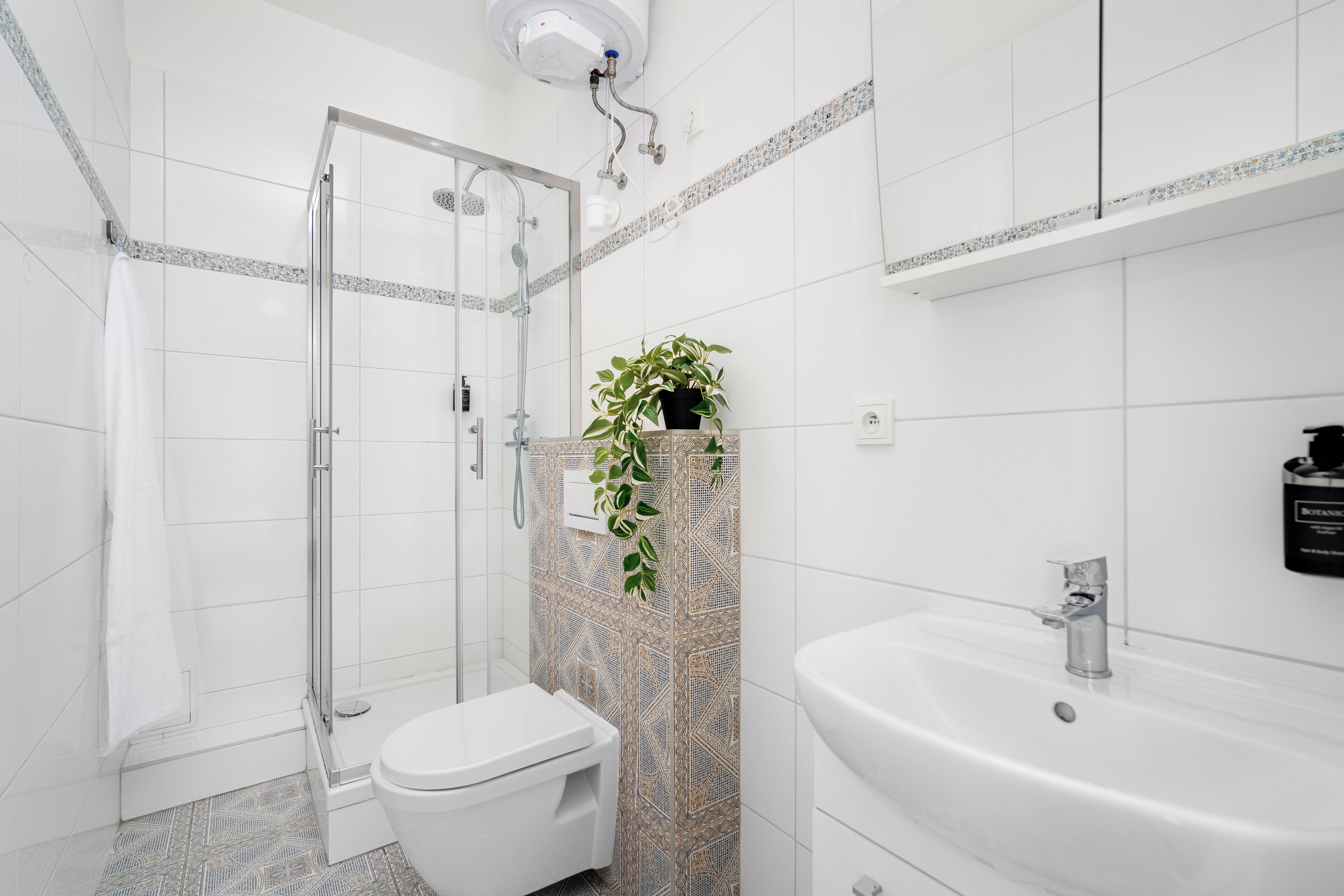 A modern bathroom with a glass-enclosed shower, a white toilet, and a sink with a mirror.