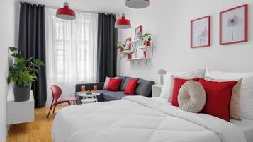 Une chambre d’hôtel moderne avec un grand lit, un canapé, une petite table et une plante en pot.