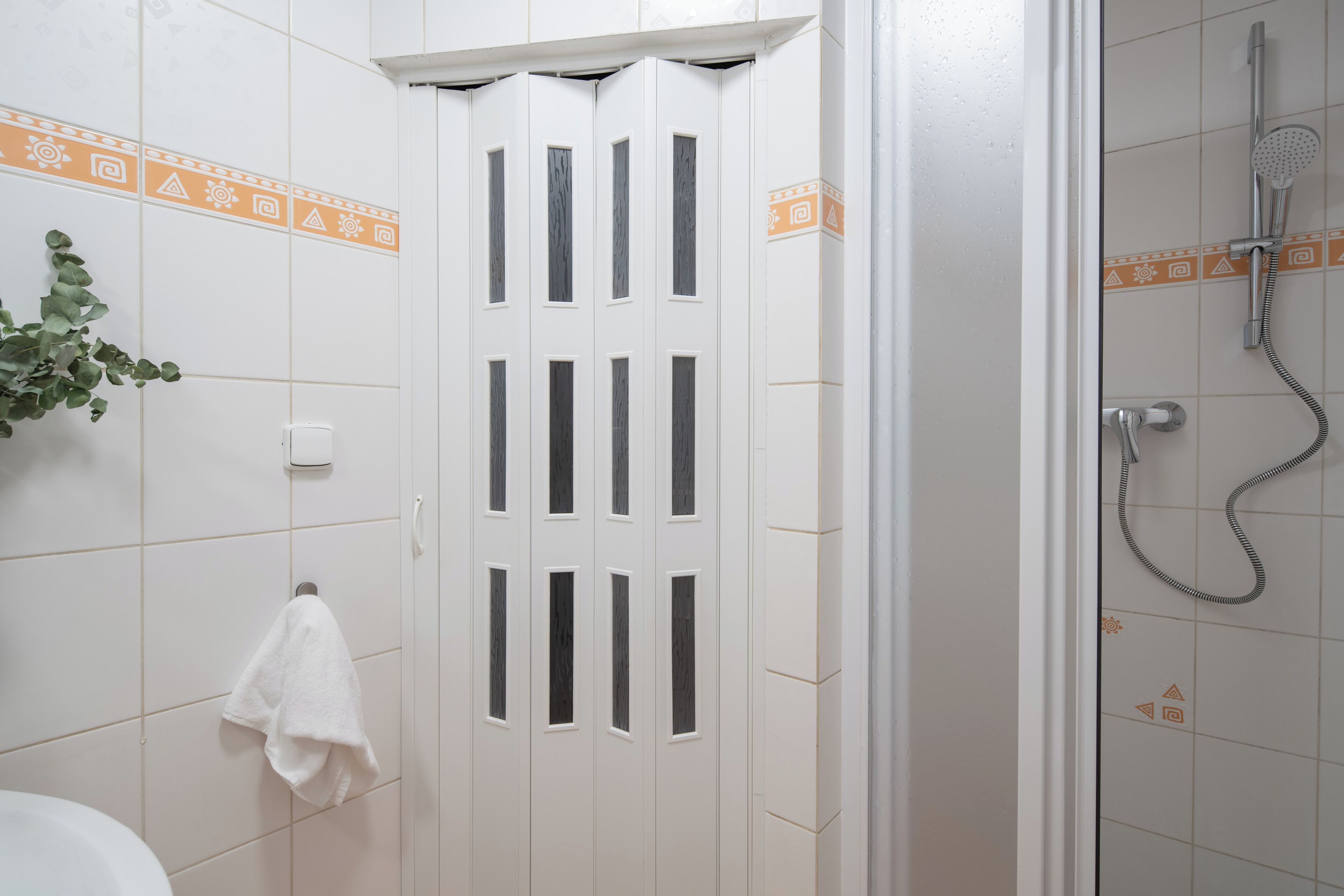 Une salle de bain avec une porte blanche, une serviette accrochée au mur et un espace douche.
