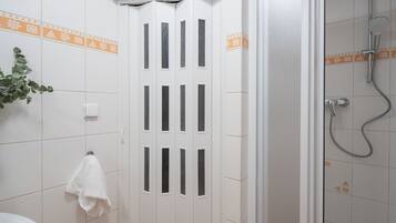 Une salle de bain avec une porte blanche, une serviette accrochée au mur et un espace douche.