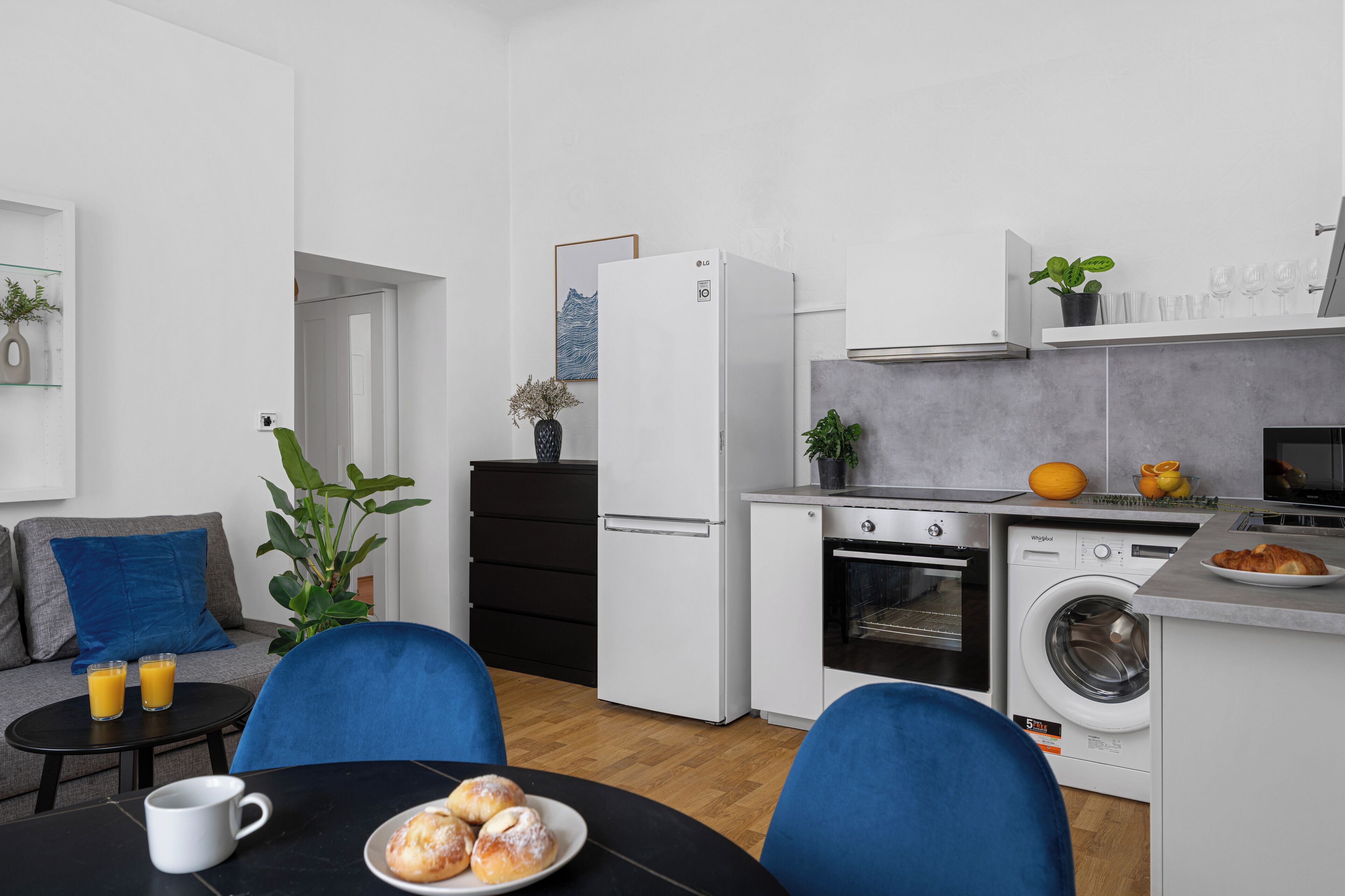 Une cuisine compacte équipée d’un lave-linge, d’un réfrigérateur et d’un coin repas avec une table et des chaises.