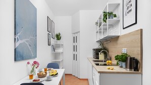 A compact kitchen with a dining area, white cabinetry, and a blue abstract painting. - Enjoy Downtown Boutique Apartments #12 by Goodnite cz (Brno)