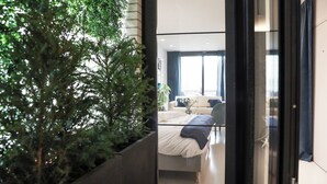 A modern hotel room with a large window, a bed, and a potted plant. - Suite Aux Anges (Antwerp)