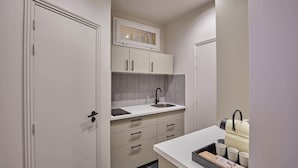 Una cocina moderna con armarios blancos, un grifo negro y una encimera con un hervidor y tazas.