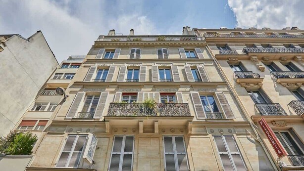 Un edificio de varios pisos con un estilo arquitectónico clásico, que presenta ventanas y balcones simétricos.