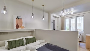 Un dormitorio moderno con cama, almohadas verdes y un cuadro en la pared.