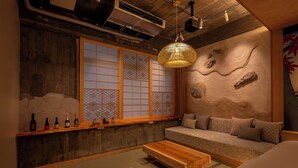 A traditional Japanese room with tatami flooring, a low wooden table, a sofa, and a large shoji screen window. - Walking distance from Asakusa, Japanese modern in Asakusa｜ 1 floor for private use｜ Ideal for couples and honeymooners｜ 30 square meters｜ Max 4 people (Matsugaya, Taito City)