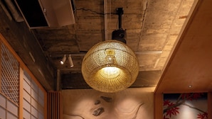 A traditional Japanese-style room with tatami flooring, a low wooden table, a sofa with cushions, and a hanging lamp. - Walking distance from Asakusa, Japanese modern in Asakusa｜ 1 floor for private use｜ Ideal for couples and honeymooners｜ 30 square meters｜ Max 4 people (Matsugaya, Taito City)