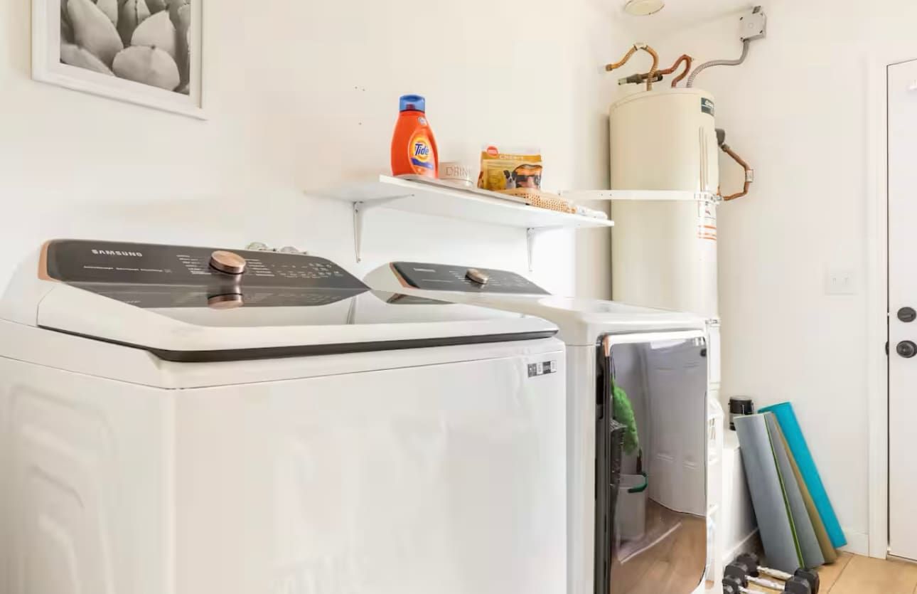 A laundry area with a Samsung washing machine, a dryer, and a water heater.