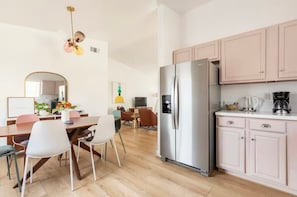 A modern kitchen with a stainless steel refrigerator, wooden cabinets, and a dining area with a table and chairs. - Kid-Ready Retreat: Lake Isabella Fun (Lake Isabella)
