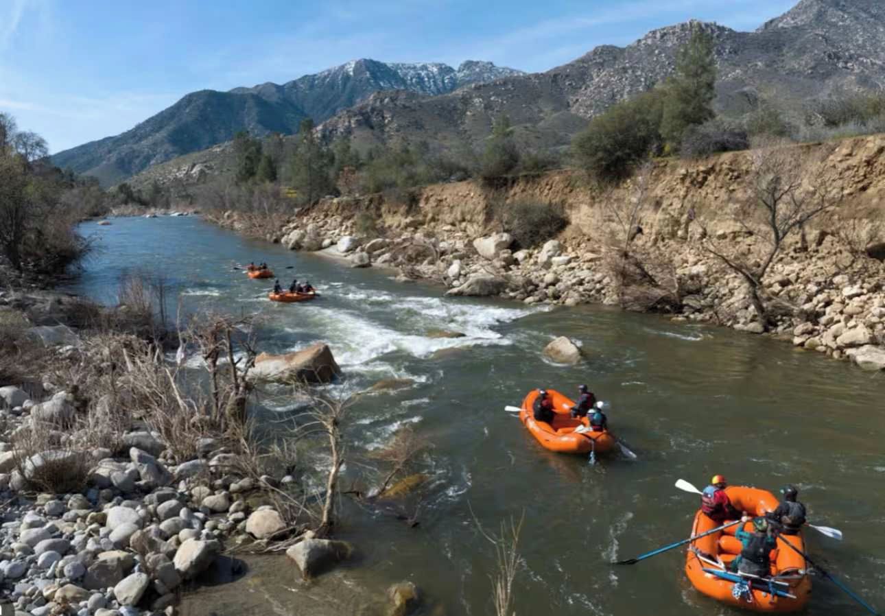 Ein Fluss mit drei orangenen Schlauchbooten.