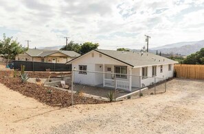 A single-story house with a fenced yard, a small porch, and a clear view of the surrounding landscape.