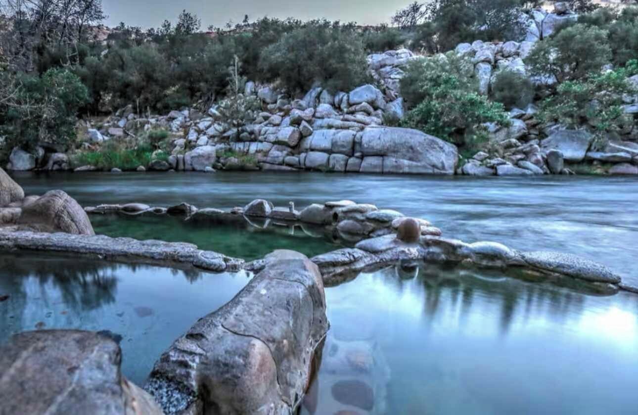 A natural landscape with a river, rocks, and trees.