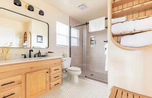 Un baño moderno con tocador de madera, cabina de ducha de vidrio y toallero empotrado.