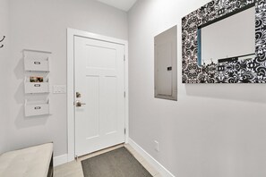 A hallway with a white door, a wall-mounted light switch, a power outlet, and a patterned wall decoration. - 5 Bed 5 Bath Mountain Oasis with Private Hot Tub (Eden)