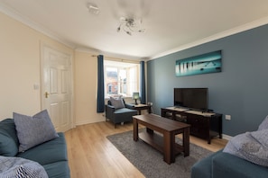A living room with a sofa, a coffee table, a TV stand, and a painting on the wall. - Toast Stays - Hillbrook (Thornaby)