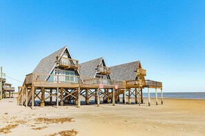 A beachfront property with wooden structures elevated on stilts, featuring multiple decks and balconies. - Unique Beachfront Escape Directly Over The Ocean (Surfside Beach)