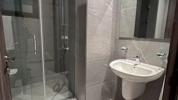 A modern bathroom with a glass shower enclosure, a sink, and a mirror.