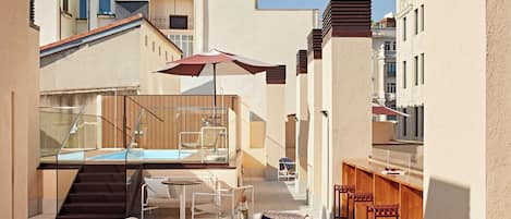 Eine Dachterrasse mit Swimmingpool, Sitzgelegenheiten im Freien und einer Bar.