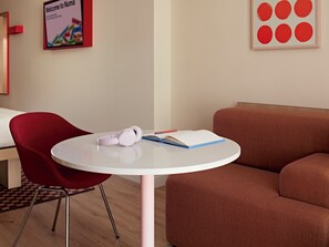 A modern room with a round table, a red chair, a sofa, and a poster on the wall. - Numa Madrid Fuencarral (Madrid)