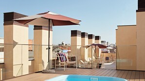 Piscina en la azotea con sillones de descanso y sombrillas.