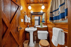 Ein Badezimmer in einer Holzhütte mit Waschbecken, Toilette und aufgehängten Handtüchern.