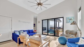 A spacious living room with a blue sofa, striped armchair, and a wooden coffee table.