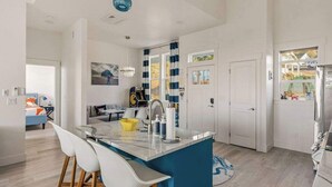 A modern kitchen with a central island, white cabinetry, and a blue accent wall.
