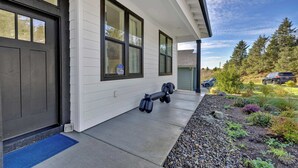 A modern house with a concrete porch, a black door, and a blue mat at the entrance.