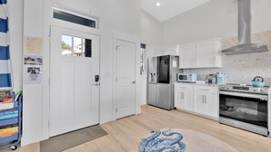 A modern kitchen with white cabinets, stainless steel appliances, and a blue octopus rug.