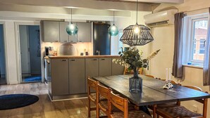 Eine moderne Küche mit dunklen Schränken, einem Holztisch und zwei Pendelleuchten.