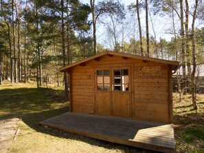 A small wooden cabin with a wooden deck in a forested area. - 8 Person Holiday Home in Aakirkeby (Akirkeby)