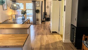 Eine geräumige Küche mit Holzboden, einem Essbereich mit Holztisch und einem schwarzen Kühlschrank.