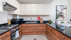 Eine moderne Küche mit Holzausstattung, einem Edelstahl-Spülbecken und einer schwarzen Arbeitsplatte.