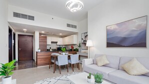 Ein modernes Wohnzimmer mit Sofa, Esstisch mit Stühlen, Küchenzeile und Flur.