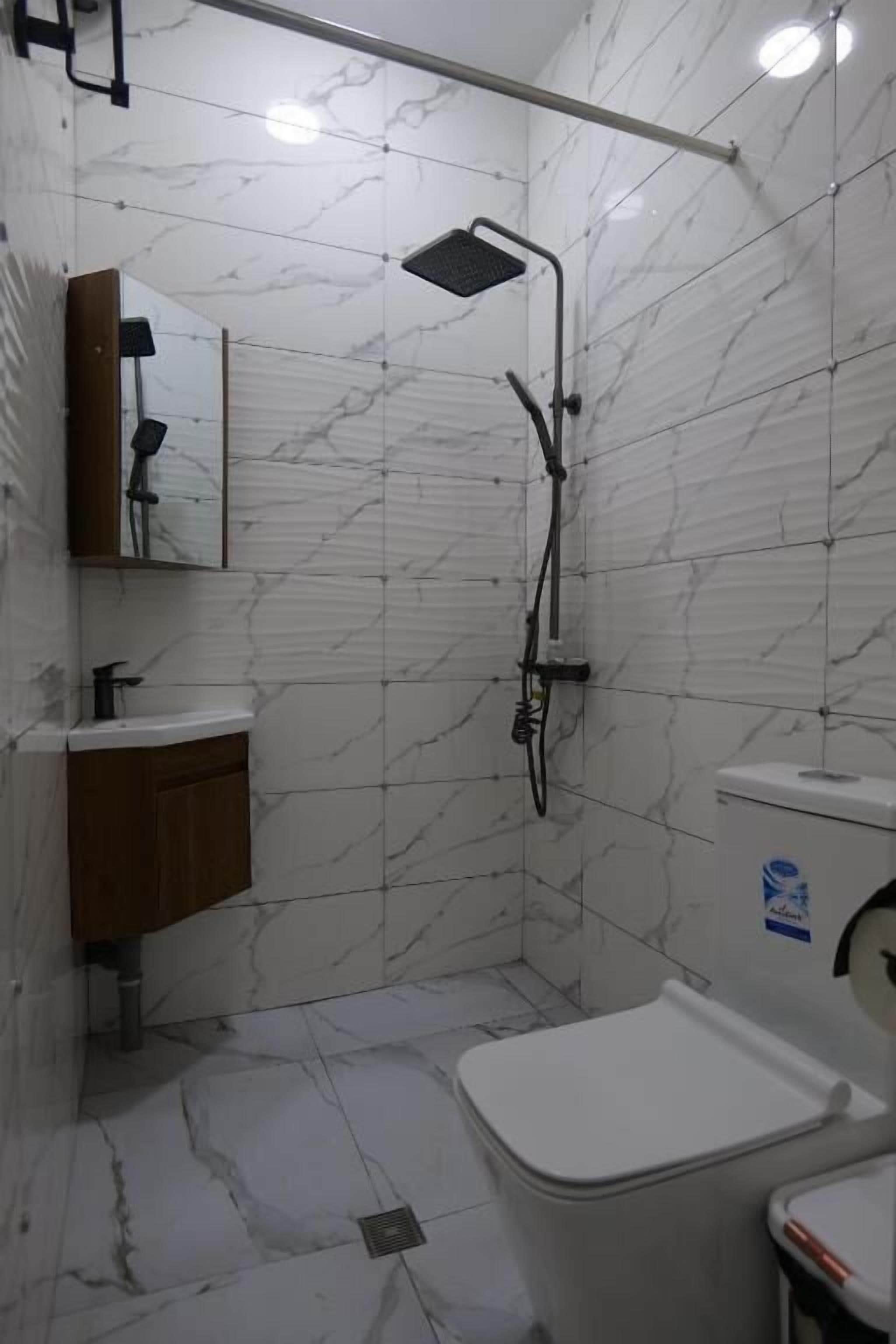 Un baño pequeño con ducha, inodoro, lavabo y espejo.