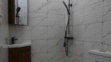Un baño pequeño con ducha, inodoro, lavabo y espejo.