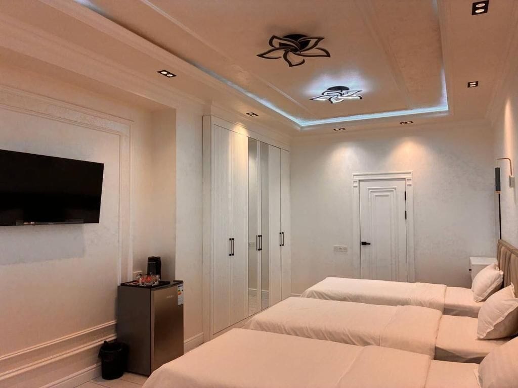 Quarto de hotel com duas camas, televisão de tela plana, minibar e teto com iluminação embutida.