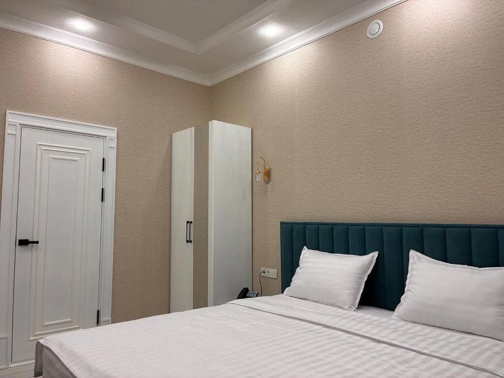 Una habitació d'hotel amb un llit, un armari i una tauleta de nit.