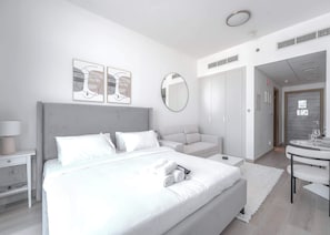 Ein modernes Schlafzimmer mit einem großen Bett, einem Nachttisch, einem runden Spiegel und einem Kleiderschrank.
